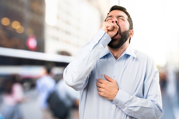 Homem bonito com barba bocejando no fundo não focado