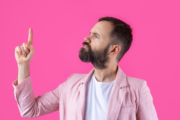 Homem bonito com barba em uma jaqueta rosa está pensando sobre um fundo vermelho isolado