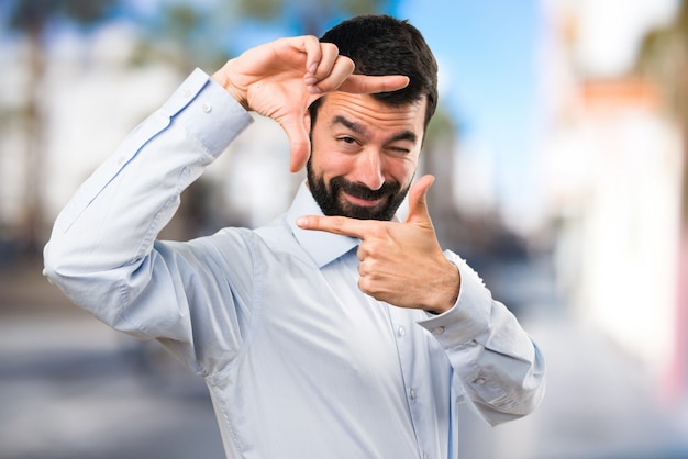 Homem bonito com barba focada com os dedos no fundo não focado