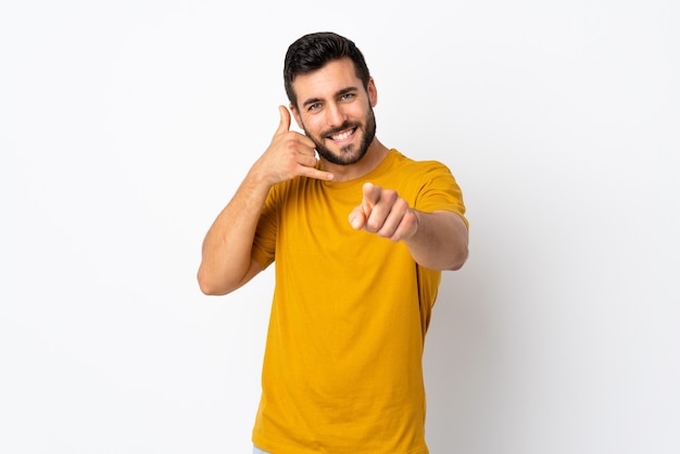 Foto homem bonito com barba isolada fazendo gesto de telefone e apontando para a frente