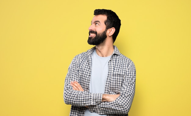 Homem bonito, com barba, olhando para cima, enquanto sorrindo