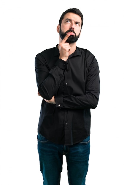 Foto homem bonito, com barba, tendo dúvidas sobre fundo branco