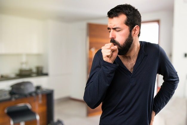 Homem bonito com barba tossindo muito dentro da casa