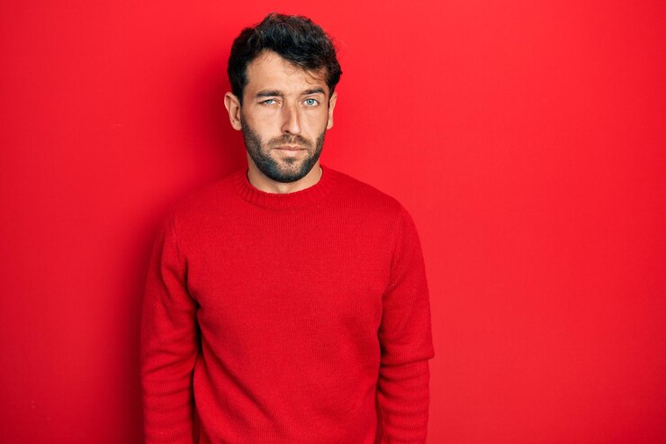 Foto homem bonito com barba vestindo suéter vermelho casual cético e nervoso carrancudo chateado por causa do problema pessoa negativa