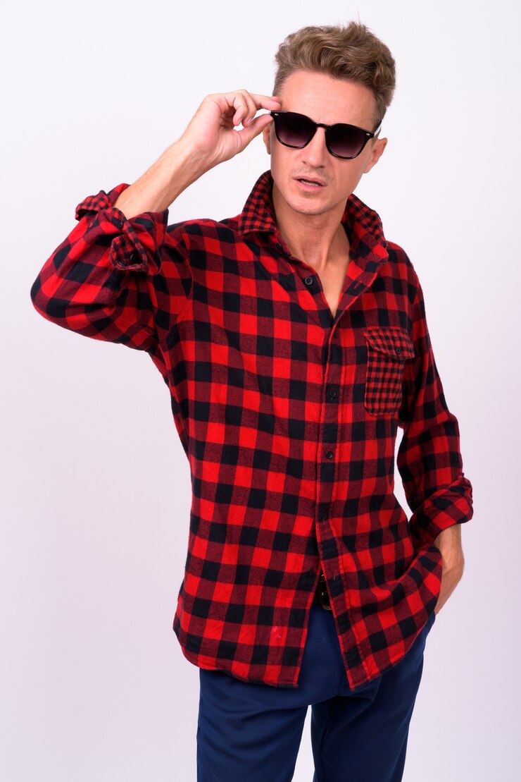 Foto homem bonito com cabelo loiro encaracolado e camisa xadrez vermelha encostada na parede branca