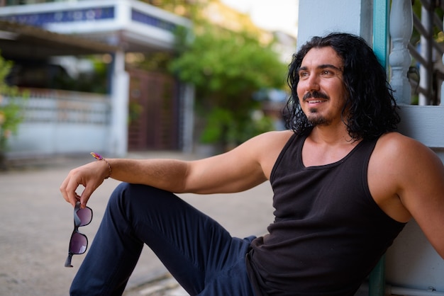 Homem bonito com cabelos cacheados e bigode na rua ao ar livre