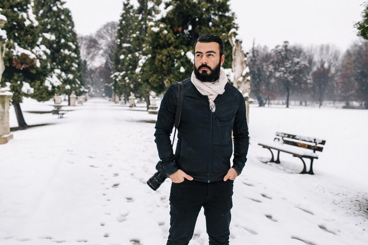 Foto homem bonito com câmera de pé na calçada coberta de neve durante o inverno