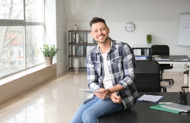 Homem bonito com computador tablet no escritório