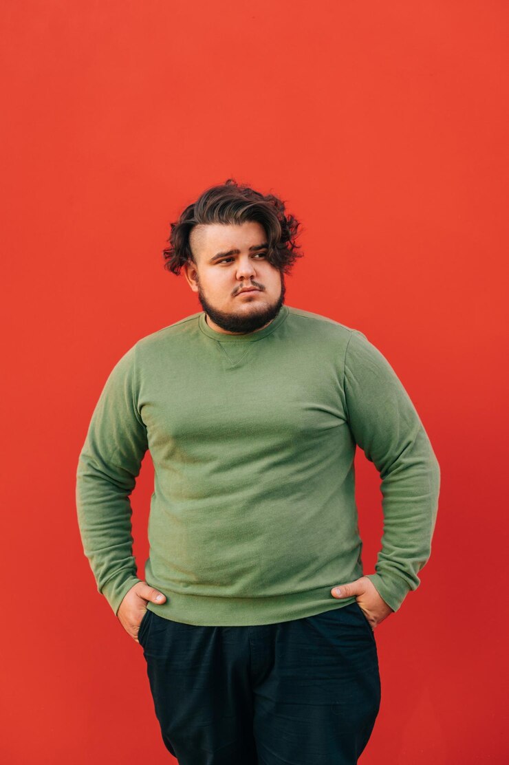 Foto homem bonito com excesso de peso com um corte de cabelo elegante e barba em um fundo vermelho isolado