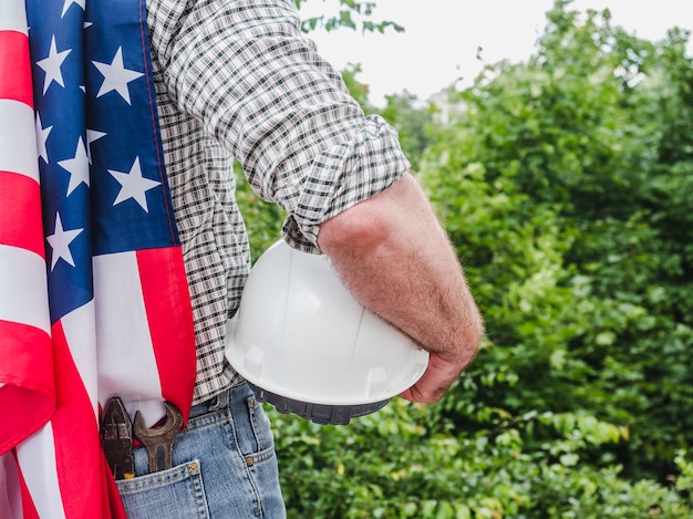 Homem bonito com ferramentas, segurando uma bandeira americana