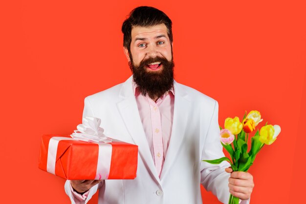 Homem bonito com flores e presente. Empresário com tulipas e presentes. Dia dos Namorados