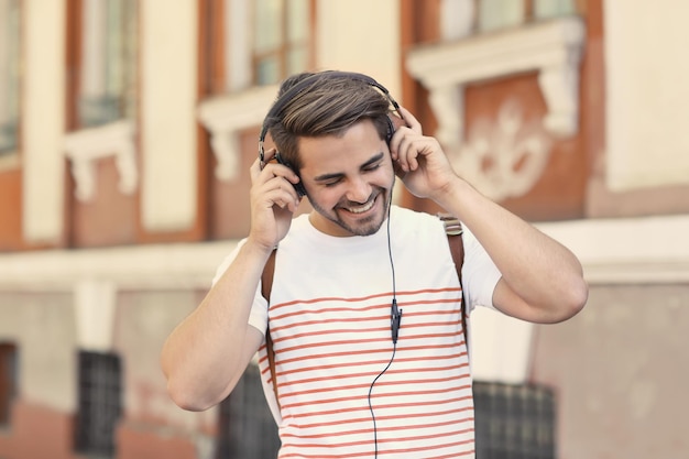 Homem bonito com fones de ouvido ouvindo música na rua