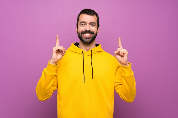 Homem bonito com moletom amarelo apontando uma ótima idéia