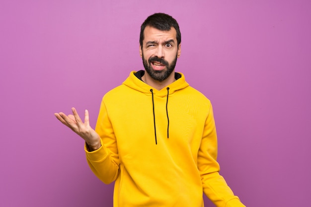 Homem bonito com moletom amarelo fazendo dúvidas gesto