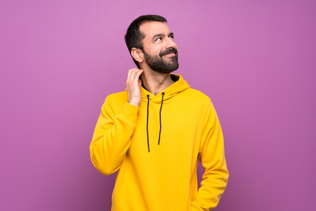 Homem bonito com moletom amarelo pensando uma idéia