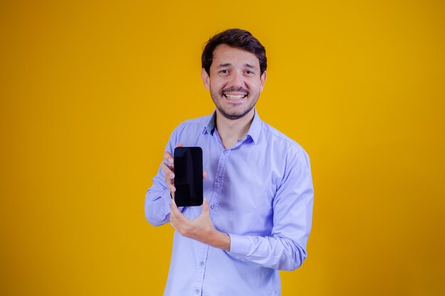 Homem bonito com o celular nas mãos apontando com espaço para texto