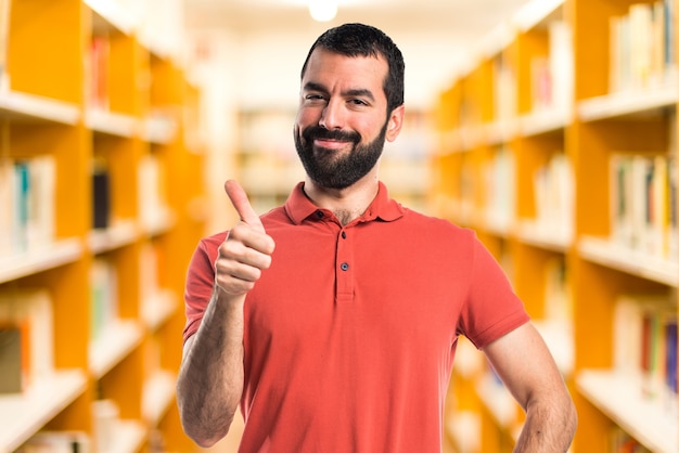 Homem bonito com o polegar acima no fundo não focado