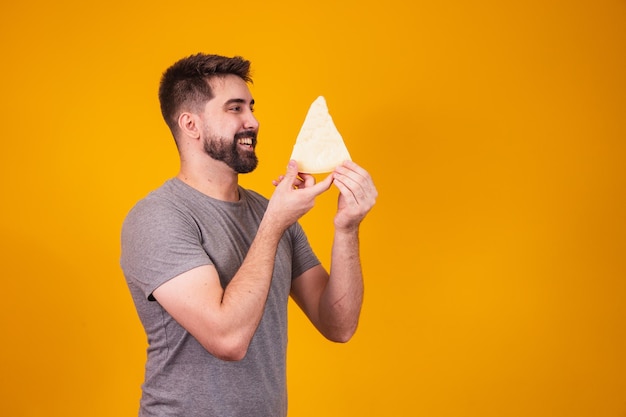 Homem bonito com pedaço de queijo em fundo amarelo. menino com uma fatia de queijo na mão