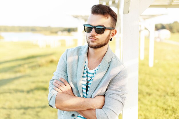 Homem bonito com roupas da moda, descansando na praia.