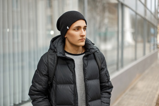 Homem bonito com roupas de inverno e mochila viajando pela cidade