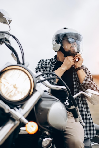 Homem bonito com sua moto na pedreira de areia