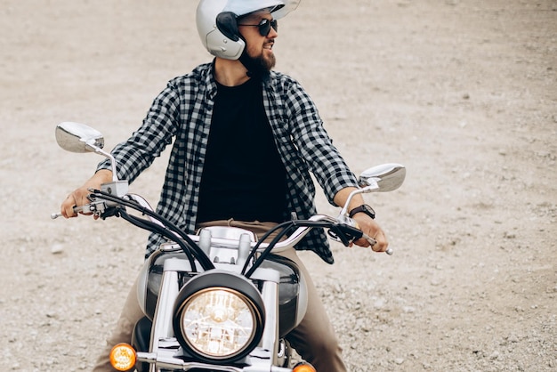 Homem bonito com sua moto na pedreira de areia