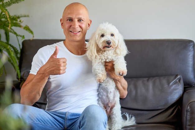 Homem bonito com um lindo cachorro branco em casa