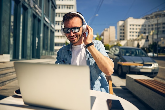 Homem bonito com um sorriso no rosto enquanto olha para a tela de seu gadget