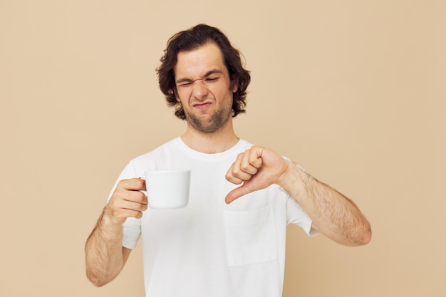 Homem bonito com uma caneca branca nas mãos emoções posando estilo de vida inalterado