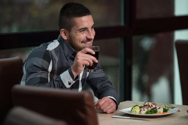 Homem bonito comendo em um restaurante e parecendo feliz