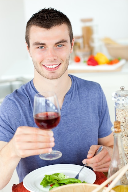 Homem bonito comendo uma salada saudável com um pouco de vinho