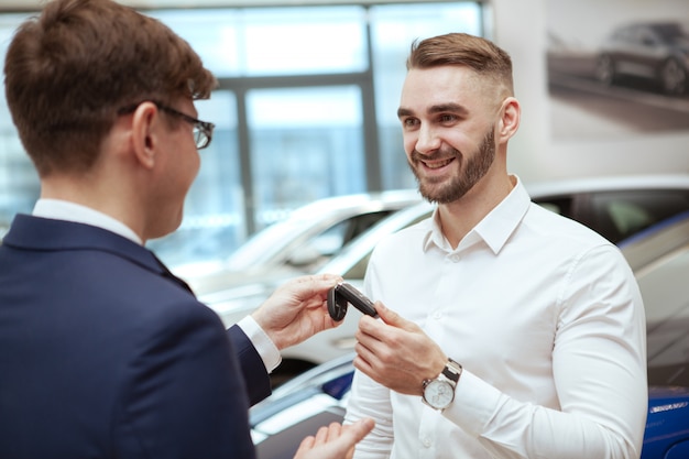 Homem bonito, comprando carro novo na concessionária