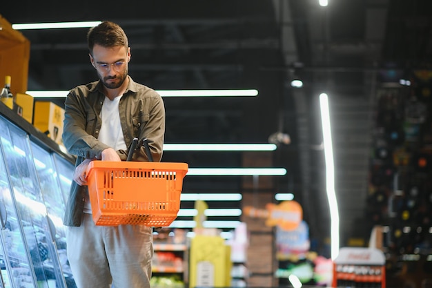 Homem bonito comprando comida e bebida saudáveis em um supermercado ou mercearia moderno Estilo de vida e conceito de consumismo