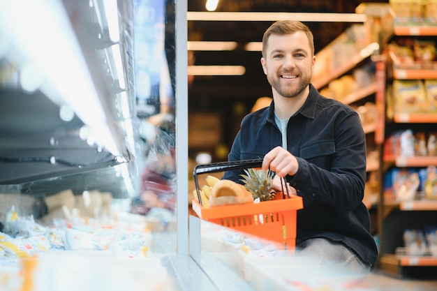 Homem bonito comprando comida e bebida saudável no supermercado moderno ou mercearia Estilo de vida e conceito de consumismo