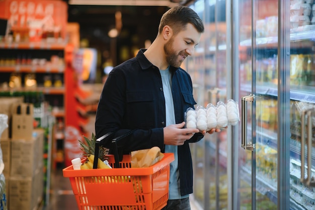 Homem bonito comprando comida e bebida saudável no supermercado moderno ou mercearia Estilo de vida e conceito de consumismo