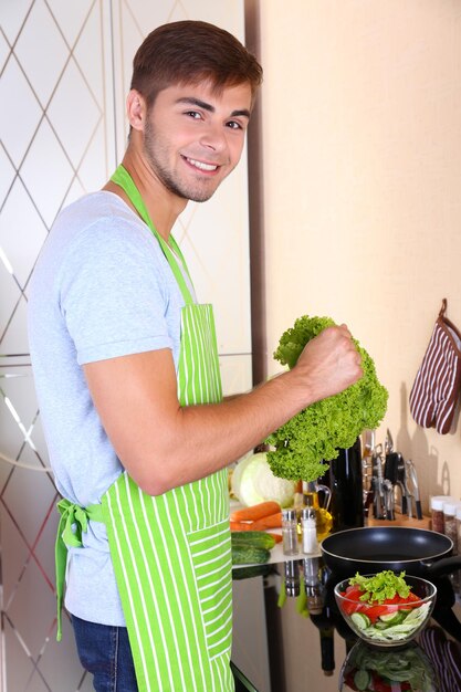 Foto homem bonito cozinhando na cozinha em casa