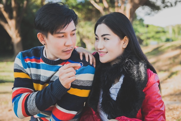 Homem bonito dá anel de ouro à sua namorada jovem casal asiático