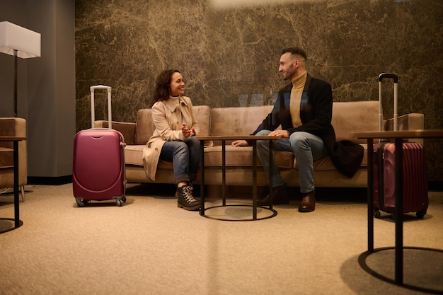 Foto homem bonito de meia-idade e mulher bonita com malas, parceiros de negócios em viagem de negócios, conversando em uma sala de reuniões enquanto aguarda o voo no terminal de embarque do aeroporto