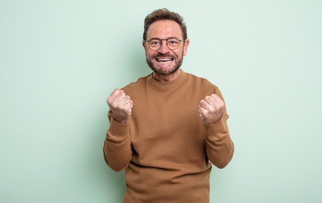 Homem bonito de meia-idade gritando triunfante, rindo e se sentindo feliz e animado ao comemorar o sucesso