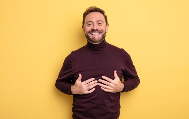 homem bonito de meia idade olhando feliz, surpreso, orgulhoso e animado, apontando para si mesmo