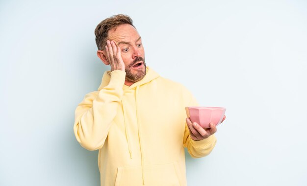 Homem bonito de meia-idade se sentindo feliz, animado e surpreso. conceito de tigela vazia