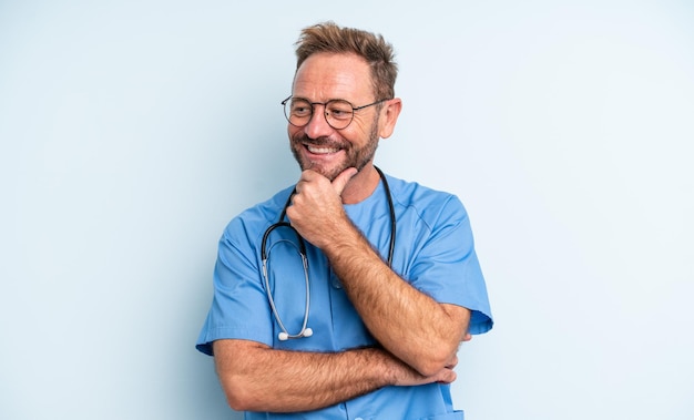 Homem bonito de meia-idade sorrindo com uma expressão feliz e confiante com a mão no conceito de enfermeira do queixo