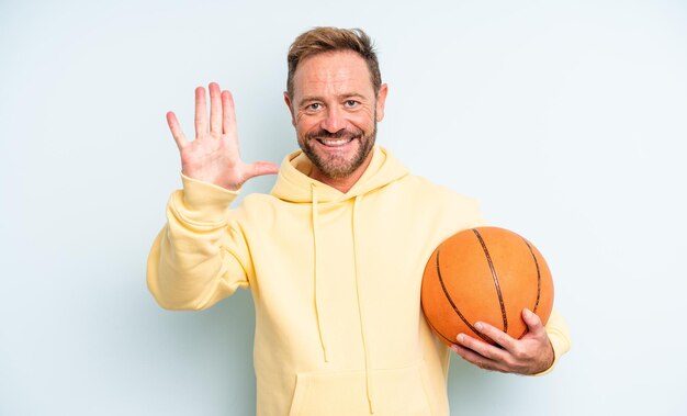 Homem bonito de meia-idade sorrindo e parecendo amigável, mostrando o número cinco. conceito de basquete