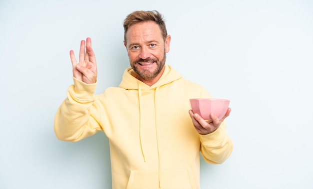 Homem bonito de meia-idade, sorrindo e parecendo amigável, mostrando o número quatro. conceito de tigela vazia