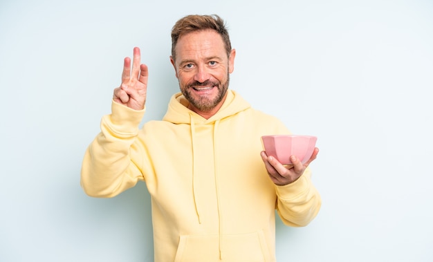 Homem bonito de meia-idade sorrindo e parecendo amigável, mostrando o número três. conceito de tigela vazia