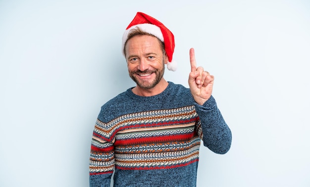 Homem bonito de meia-idade sorrindo e parecendo amigável, mostrando o número um. conceito de natal