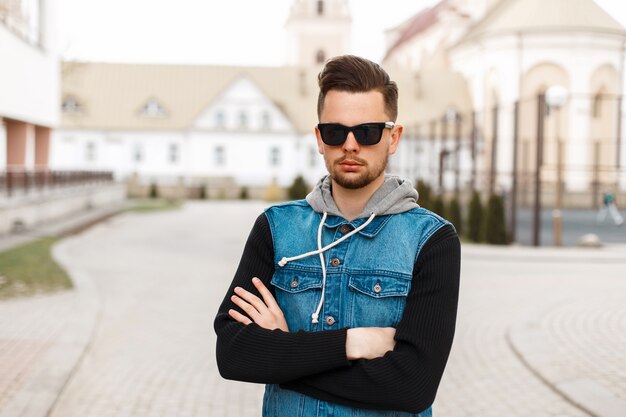 Homem bonito de óculos escuros e jaqueta jeans posando na rua