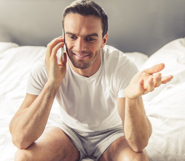 Homem bonito de pijama está falando no telefone celular