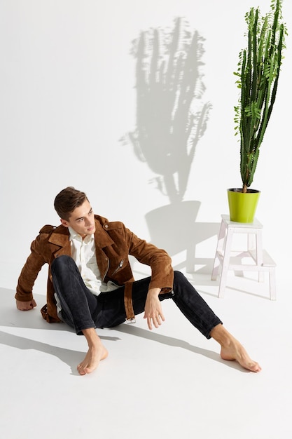 Homem bonito de terno senta-se no chão perto de uma flor em uma panela Foto de alta qualidade