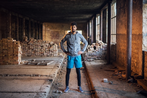 Homem bonito desportivo afro-americano pronto para o treinamento, correndo lá fora.